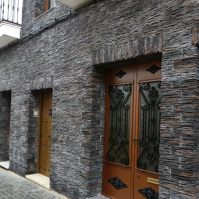 Revestimiento de piedra Galicia - Pizarra, Cantidad total: 4 pzs. - Fachada rústica con una distintiva puerta doble de entrada. Las piedras oscuras le dan al edificio un encanto natural y robusto.