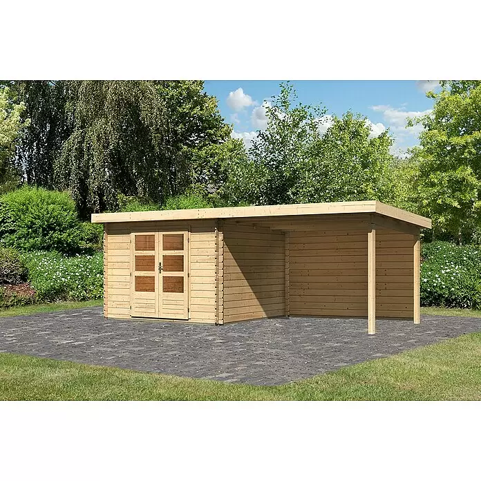 Karibu Gartenhaus Bastrup 5 - Außenmaß inkl. Dachüberstand (B x T): 614 x 333 cm, Holz, Natur, Mit Seitendach und Rückwand - Helles Gartenhaus aus Naturholz mit angebautem Carport, auf einer dunklen gepflasterten Fläche im Grünen.