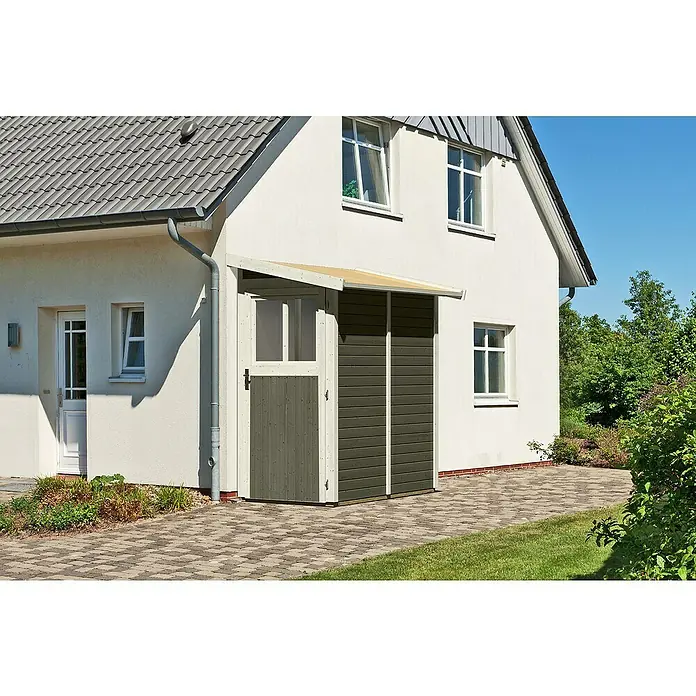 Karibu Gartenhaus Görlitz - Außenmaß inkl. Dachüberstand (B x T): 117 x 217 cm, Holz, Terragrau - Ein ansprechendes Gerätehaus aus Holz mit Vordach vor einer hellen Hauswand, umgeben von gepflastertem Boden und Grünfläche.