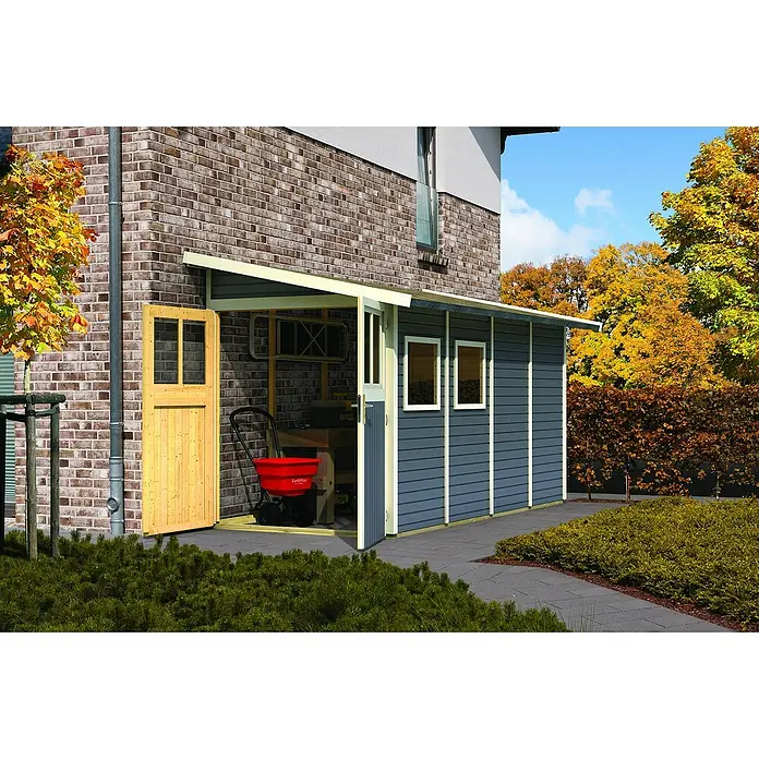 Karibu Gartenhaus Wandlitz 4 - Außenmaß inkl. Dachüberstand (B x T): 200 x 408 cm, Holz, Terragrau - Diese Aufnahme zeigt ein Gartenhaus mit einer Holztür und Werkzeugen im Inneren, umgeben von üppigem Grün. Das Gartenhaus bietet Stauraum.