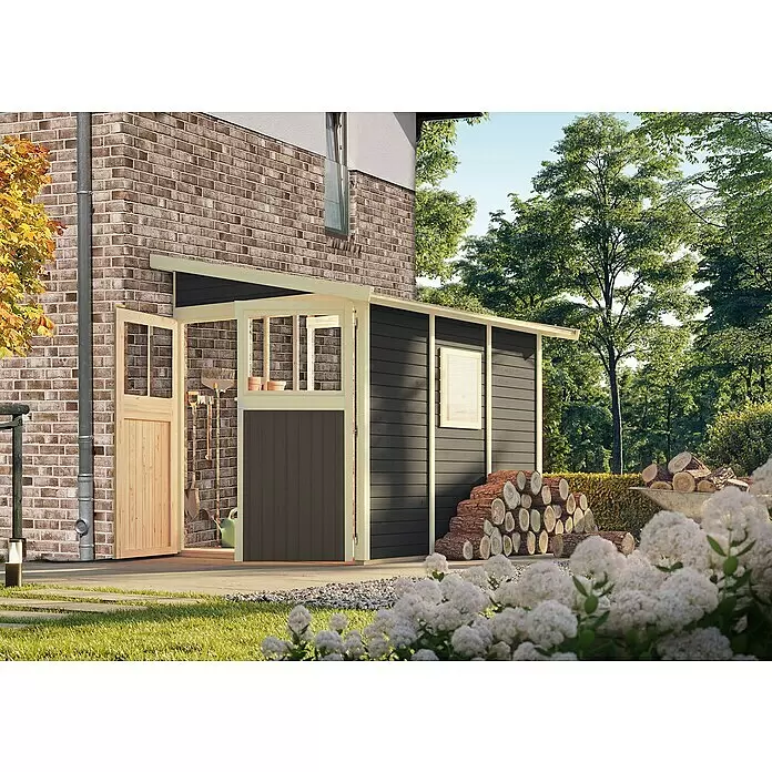 Karibu Gartenhaus Wandlitz 3 - Außenmaß inkl. Dachüberstand (B x T): 200 x 320 cm, Holz, Terragrau - Dunkelgrauer Holz-Gartenschuppen mit heller Verkleidung, an einem Backsteinhaus, mit Gartenwerkzeugen und Brennholz.