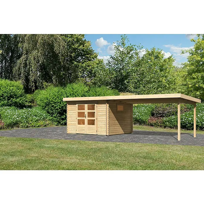 Karibu Gartenhaus - Außenmaß inkl. Dachüberstand (B x T): 716,5 x 333 cm, Holz, Natur, Mit Seitendach - Ein hellbraunes Gartenhaus mit einem Carport-Anbau, umgeben von Rasenflächen, Büschen und Bäumen unter blauem Himmel.