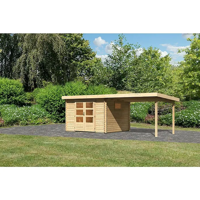 Karibu Gartenhaus Trittau 3 - Außenmaß inkl. Dachüberstand (B x T): 616,5 x 333 cm, Holz, Natur, Mit Seitendach - Ein Holzschuppen mit Vordach auf einer gepflasterten Fläche, umgeben von Rasen und üppigem Grün. Praktisch und stilvoll für jeden Garten.