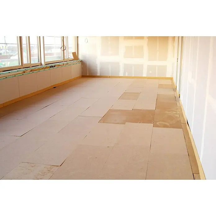 Steico Holzfaserdämmplatte base1.350 x 600 mm, Stärke: 60 mm, Wärmeleitfähigkeit: 0,048 W/(mK) - Innenaufnahme eines Raumes im Rohbau, der Boden ist teilweise mit Quadratelementen ausgelegt. Zu sehen sind zudem Fenster und verputzte Wände.