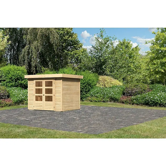 Karibu Gartenhaus Cuno 2 - Außenmaß inkl. Dachüberstand (B x T): 266 x 238 cm, Holz, Natur - Außenansicht eines hellbraunen Gartenhauses mit Doppeltür auf einem gepflasterten Bereich, umgeben von üppigem Grün.