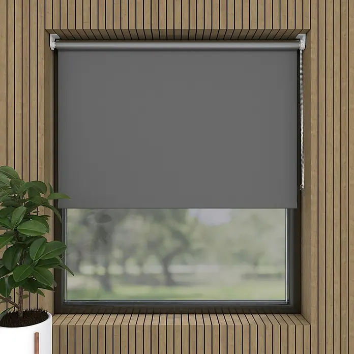 Expo Ambiente Rollo Mini - B x H: 75 x 150 cm, Grau, Uni, Verdunkelnd - Eine graue Rollo vor einem Fenster mit Holzrahmen, die teilweise heruntergezogen ist, und eine Zimmerpflanze links im Bild.