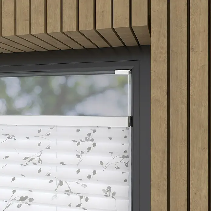 Expo Ambiente Plissee - B x H: 80 x 130 cm, Grau/Weiß - Nahaufnahme eines Fensters mit einem floral gemusterten Plissee-Rollo, umgeben von Holzpaneelen, die ein modernes Innendesign zeigen.