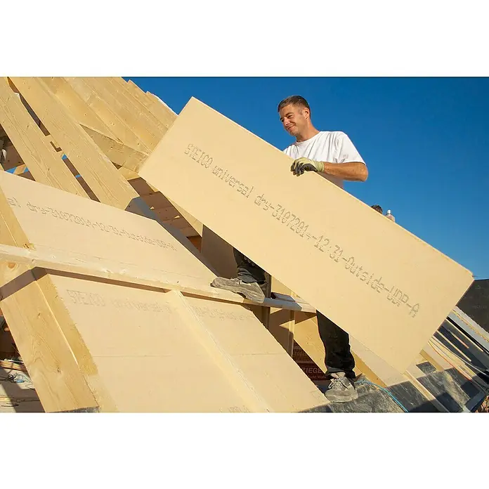 Steico Unterdeck- & Wandbauplatte universal dry - 1.880 x 600 x 60 mm, Wärmeleitfähigkeit: 0,043 W/(mK) - Mann montiert eine STEICO Holzfaserplatte auf einem Dachstuhl. Diese Platte bietet natürliche Dämmung und ist umweltfreundlich.