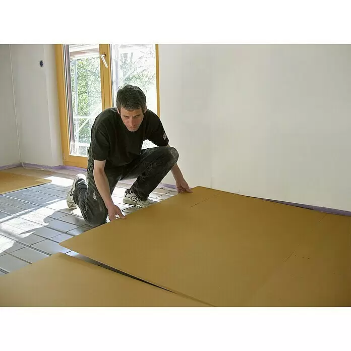 Steico Holzfaserdämmplatte therm SD - 1.350 x 600 mm, Stärke: 30 mm, Wärmeleitfähigkeit: 0,038 W/(mK) - Mann verlegt hellbraune Faserplatten zur Bodenisolierung.