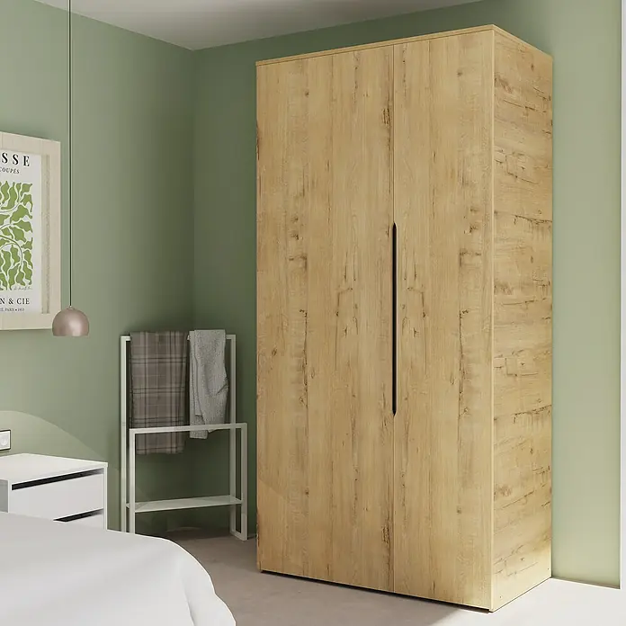 Muebles Pitarch Armario para ropa Noa - L x An x Al: 57 x 100 x 200 cm, Roble gold - Un gran armario de madera clara con dos puertas y tiradores negros se encuentra en una habitación con paredes verdes. Mucho espacio para guardar ropa.