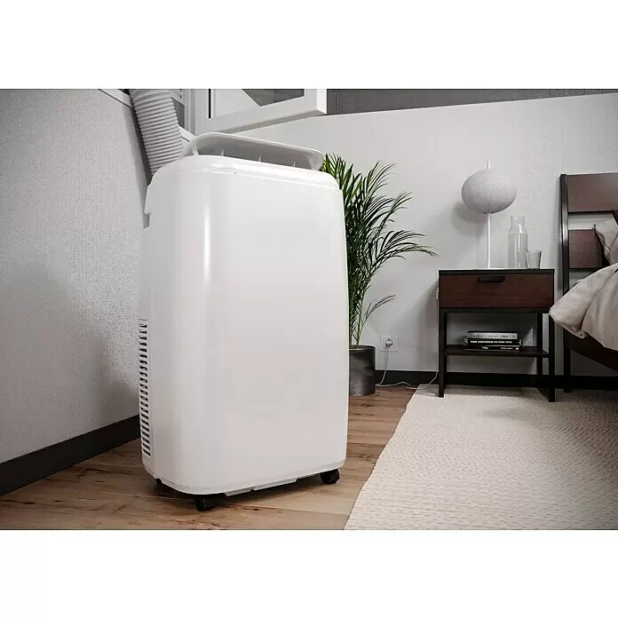 Proklima Mobiles Klimagerät WiFi - 2.500 W, Raumgröße: 24 m², Weiß - Weißes, mobiles Klimagerät in einem Schlafzimmer, Abluftschlauch zum Fenster führend.