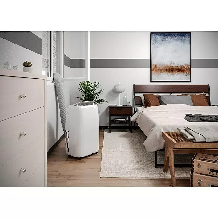 Proklima Mobiles Klimagerät WiFi - 2.500 W, Raumgröße: 24 m², Weiß - Weißes mobiles Klimagerät im Schlafzimmer, mit Abluftschlauch zum Fenster.