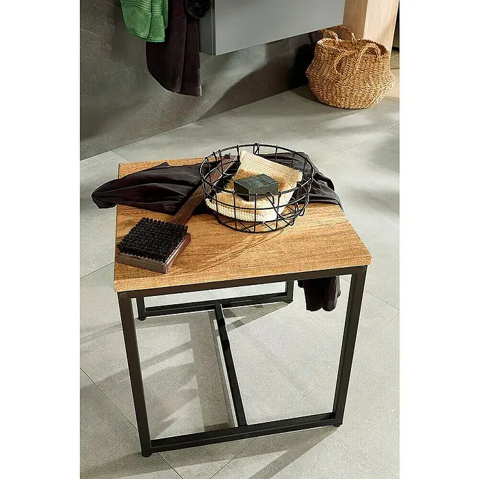 Astor Tree Badhocker - B x H: 43,5 x 46 cm, Eiche/Schwarz - Quadratischer Tisch mit Holzplatte und Metallrahmen, darauf Badutensilien wie Bürste, Seife und Handtuch. Eine Korbtasche steht im Hintergrund.