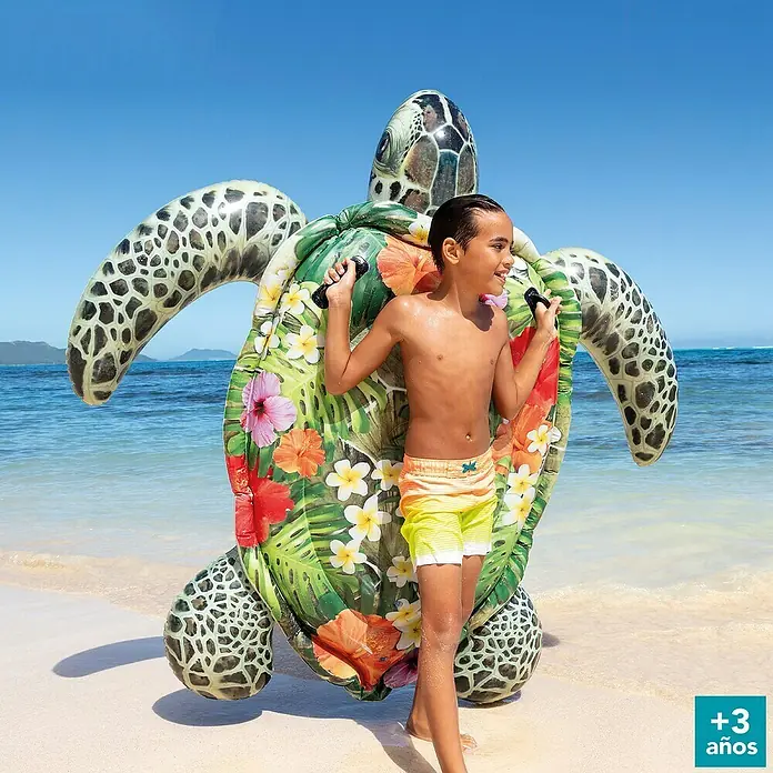 Intex Animal acuático Tortuga - 197 x 170 x 26 cm, Plástico - Un niño en la playa sosteniendo una tortuga inflable con un estampado floral. ¡El juguete acuático perfecto para niños a partir de 3 años!