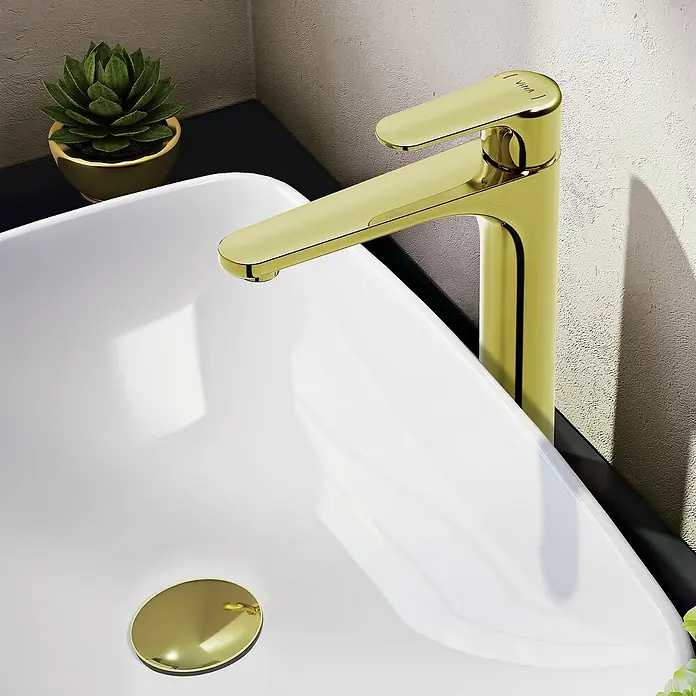 VitrA Waschtischarmatur Root Round - Höhe: 31,5 cm, Gold - Nahaufnahme einer modernen goldenen VITA Badarmatur auf einem weißen Waschbecken mit einer kleinen Pflanze im Hintergrund.