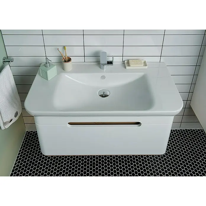 VitrA Sento Badmöbel-Set - 98 cm, Weiß, Griffmulde - Modernes Waschbecken mit weißem Unterschrank und Armatur, Zahnputzbecher, Seife und Handtuch. Die sechseckigen Bodenfliesen bilden einen Kontrast.