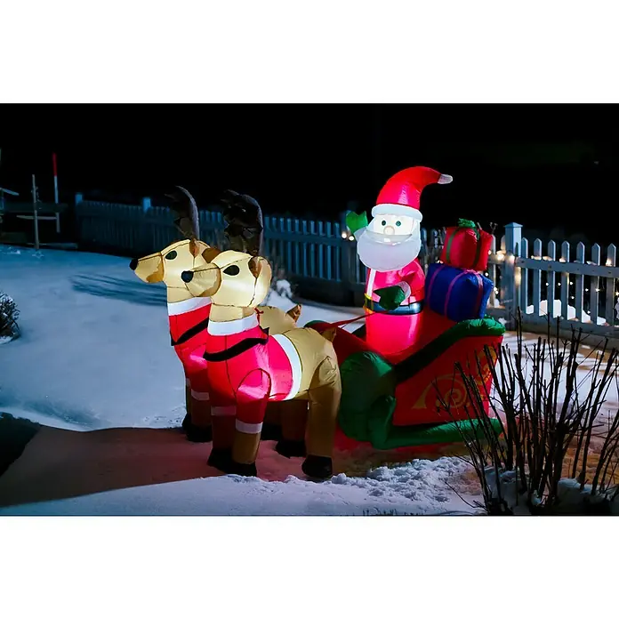 Figura LED navideña Papá Noel hinchable con renos - 180 x 75 x 140 cm, Multicolor, Funcionamiento en red, LED - Decoración navideña inflable con Santa y renos, expuesta sobre una superficie nevada frente a una valla blanca.
