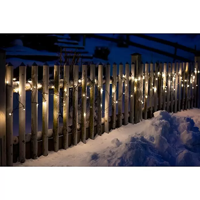 Tween Light LED-Lichterkette - Außen, Lichtfarbe: Warmweiß, Anzahl Leuchtmittel: 200 Stk., Netzbetrieben, 35 m - Warmweiße Lichterkette beleuchtet einen schneebedeckten Holzzaun in der Nacht.
