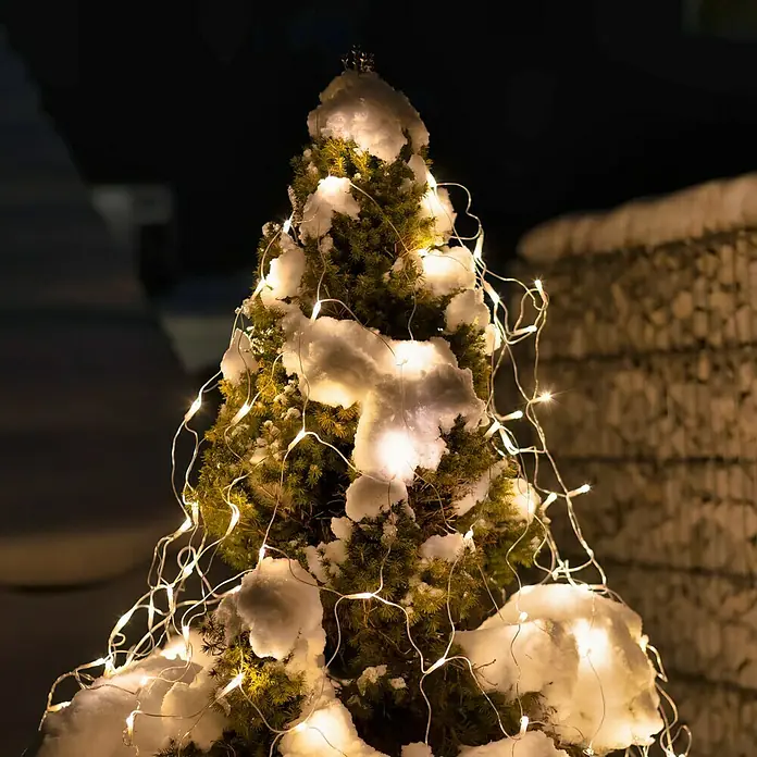 Tween Light LED-Lichtnetz - Außen, 2 m, Lichtfarbe: Warmweiß, Netzbetrieben - Ein schneebedeckter, mit Lichtern geschmückter Baum strahlt winterliche Wärme aus.