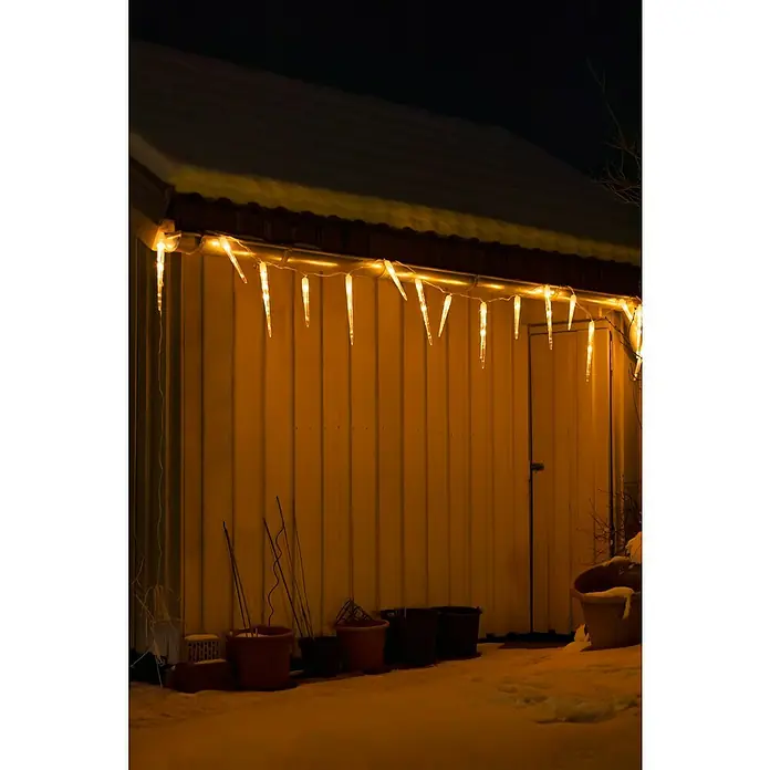 Konstsmide LED-Lichtervorhang Eiszapfen - Außen, 13,75 m, Bernstein, 24 Stk., Netzbetrieben - Festliche Dekoration: Beleuchtete Eiszapfen-Lichterkette hängt an der Fassade eines Hauses und erzeugt eine warme, weihnachtliche Atmosphäre.