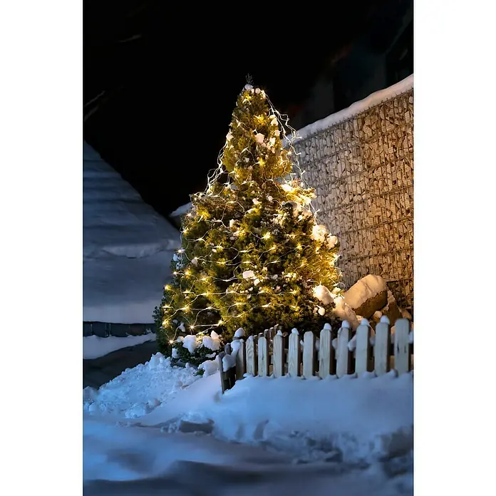 Tween Light LED-Lichtnetz - Außen, 2 m, Lichtfarbe: Warmweiß, Netzbetrieben - Beleuchteter Weihnachtsbaum mit Lichterketten im Schnee, umgeben von einem Holzzaun.