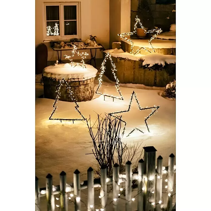 LED-Gartenstecker Stern M - Außen, Netzbetrieben, Höhe: 102 cm, Warmweiß - Leuchtende Stern- und Baum-Weihnachtsdekorationen im Freien auf verschneitem Boden bei Nacht. Ein beleuchteter Zaun ist im Vordergrund.