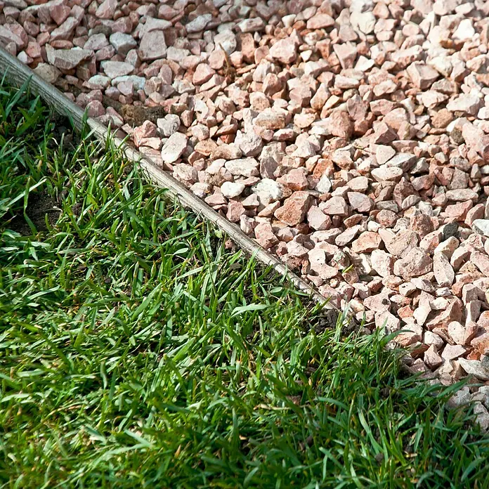 Lámina de drenaje Espuma - 1,5 x 1,5 m, Azul - Primer plano de césped junto a grava rosa decorativa, separado por borde de madera, ideal para diseño de jardines y paisajismo.