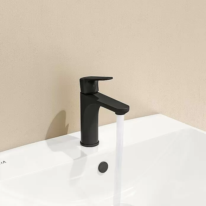VitrA Waschtischarmatur Root Round - Schwarz - Mattschwarzer Wasserhahn mit fließendem Wasser in einem weißen Keramikwaschbecken.
