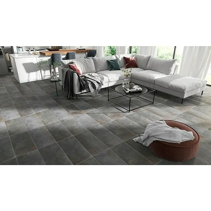 Feinsteinzeugfliese Metallbeton - 30 x 60,4 cm, Hellgrau, Matt - Dieses Bild zeigt graue Bodenfliesen in einem modernen Wohnraum, der durch ein großes Sofa und natürliche Lichtquellen hervorgehoben wird.