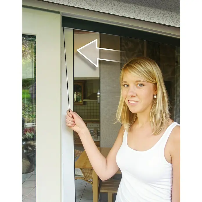Schellenberg Insect Stop Mosquitera Premium - An x Al: 95 x 220 cm, Pegado, Color bastidor: Antracita - Una mujer abre una puerta con una mosquitera. La mosquitera ofrece una protección fiable contra los insectos.