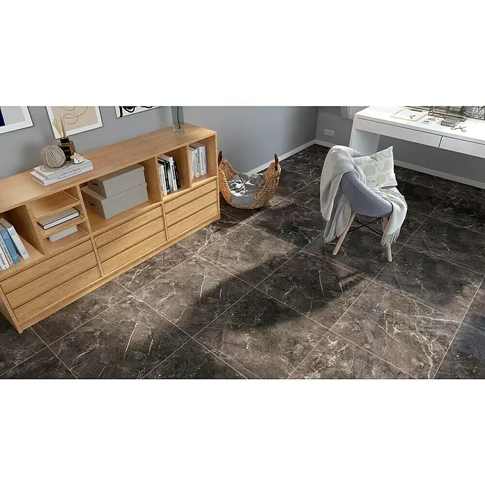 Feinsteinzeugfliese Premium Marble - 60 x 60 cm, Anthrazit, Glänzend - Elegantes Interieur mit dunklem Marmorboden, einem hellen Holzschrank und einem gemütlichen Stuhl mit Decke. Stilvolles Wohnambiente.