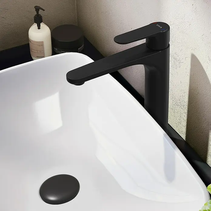 VitrA Waschtischarmatur Root Round - Höhe: 31,5 cm, Schwarz - Nahaufnahme eines schwarzen Wasserhahns und eines weißen Waschbeckens mit Pflegeprodukten. Elegantes und modernes Design für Badezimmer.