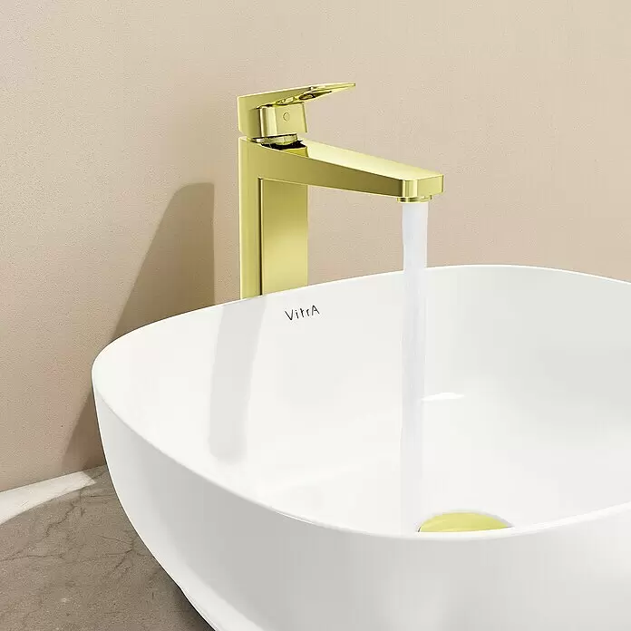 VitrA Waschtischarmatur Root Square - Höhe: 31 cm, Gold - Ein moderner goldener Wasserhahn mit fließendem Wasser in ein weißes Aufsatzwaschbecken von VitrA.