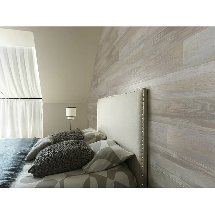 Grosfillex Panel de pared Element Wood Compact Datcha - Gris, 120 cm x 15,4 cm x 6 mm - Un dormitorio con una cama con cabecero tapizado en gris claro frente a una pared con paneles de madera.