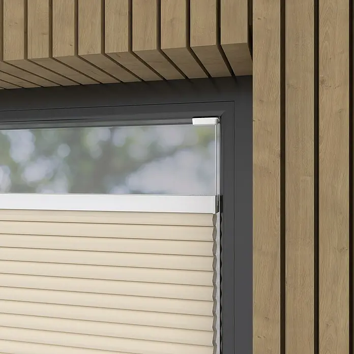 Expo Ambiente Wabenplissee - B x H: 50 x 130 cm, Sand, Verdunkelnd - Nahaufnahme einer beigefarbenen Plissee-Jalousie an einem Fenster mit grauem Rahmen und einer Holzpaneelwand im Hintergrund.
