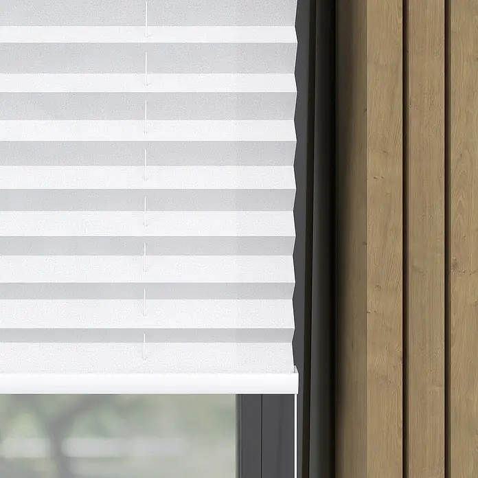 Plissee Basic VS TL - B x H: 75 x 130 cm, Weiß - Nahaufnahme einer weißen Plissee-Jalousie vor einem Fenster mit Holzverkleidung, die eine elegante Fensterdekoration zeigt.