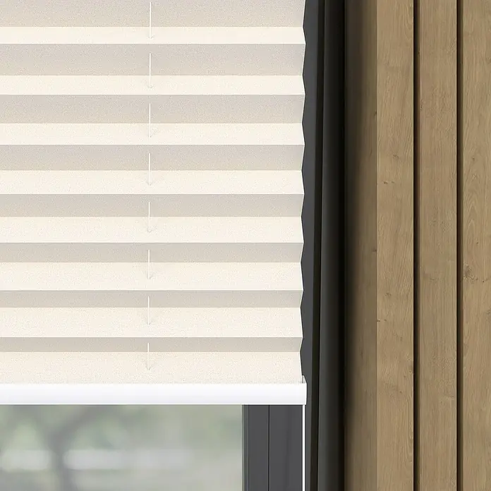 Plissee Basic VS Thermo - B x H: 45 x 130 cm, Altweiß, Verdunkelnd - Nahaufnahme einer beigen Plissee-Jalousie vor einem Fenster und einer Holzwand.