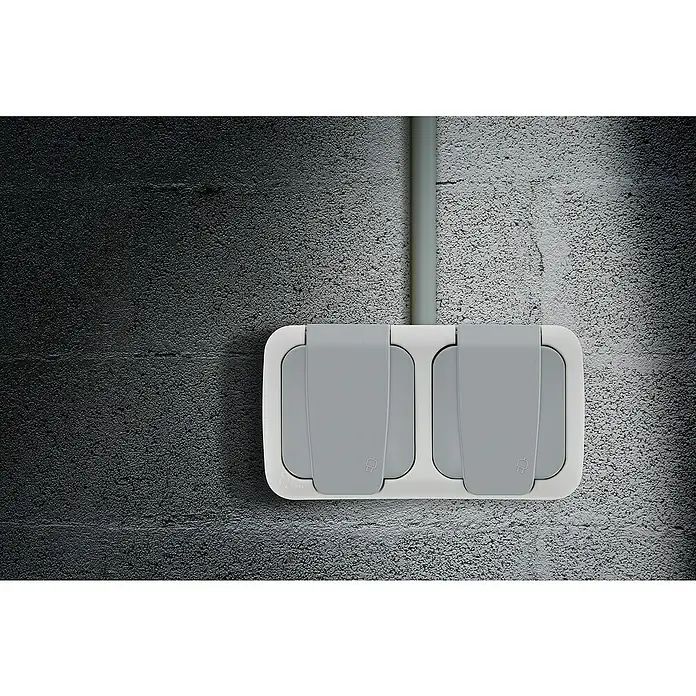 Siemens Delta IP54 Feuchtraum-Steckdose SIE028684 - 2-fach, IP54, Grau - Nahaufnahme einer Doppelsteckdose mit Schutzklappen an einer Betonwand, ideal für den Außenbereich.