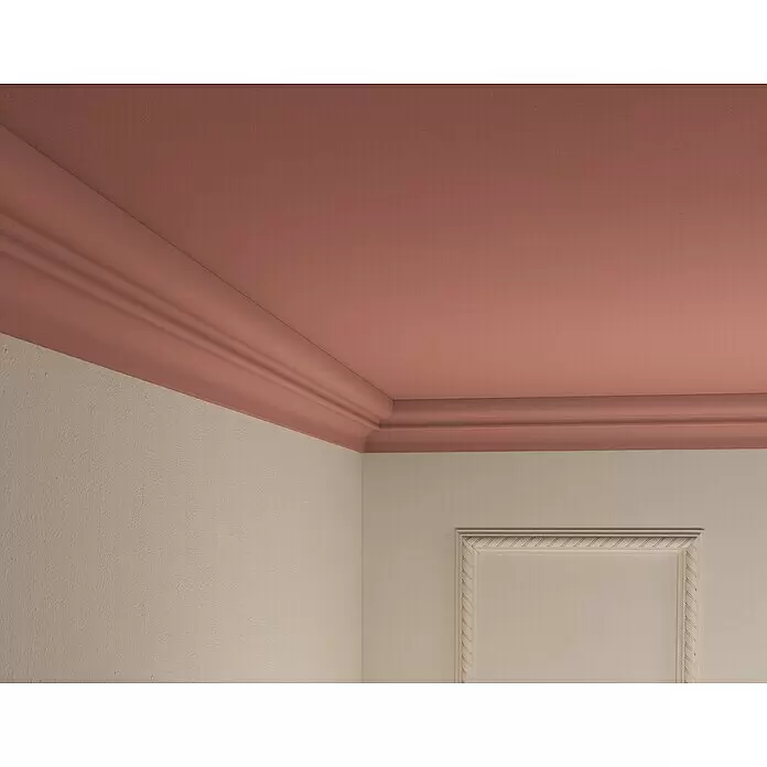Nmc Decoflair Zierprofil Deckenleiste D14 - 2 m x 66 mm x 83 mm, Extrudiertes Polystyrol (XPS) - Raumecke mit lachsfarbener Decke und aufwendiger Kranzleiste, abgesetzt von hellbeigen Wänden. Eine Wand hat eine dekorative Rahmenverkleidung.