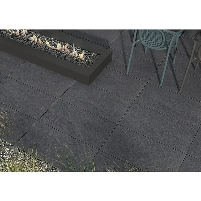 Terrassenfliese Kamari 2.0 - 39,7 x 79,7 x 2 cm, Anthrazit, Matt - Terrassenplatten aus dunklem Stein mit modernem Kamin und Stühlen, ideal für stilvolle Außenbereiche.