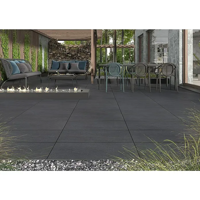 Terrassenfliese Kamari 2.0 - 39,7 x 79,7 x 2 cm, Anthrazit, Matt - Außenbereich mit großformatigen, anthrazitfarbenen Bodenfliesen, ergänzt durch stilvolle Gartenmöbel und eine moderne Feuerstelle, die ein einladendes Ambiente schaffen.