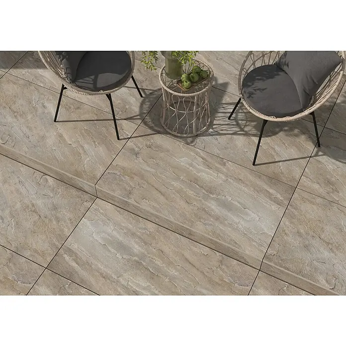 Terrassenfliese Sasso 2.0 - 59,7 x 119,7 x 2 cm, Grau, Matt - Nahaufnahme von zwei Stühlen und einem Tisch auf einem sandfarbenen Fliesenboden, der eine stilvolle Außenatmosphäre schafft.