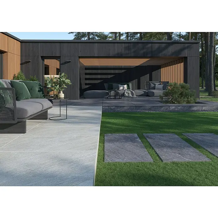 Terrassenfliese Piazza 2.0 - 59,7 x 119,7 x 2 cm, Sabbia, Matt - Das Bild zeigt elegante Terrassenplatten im Außenbereich, die sich harmonisch in die grüne Umgebung einfügen. Die grauen Platten wirken modern.