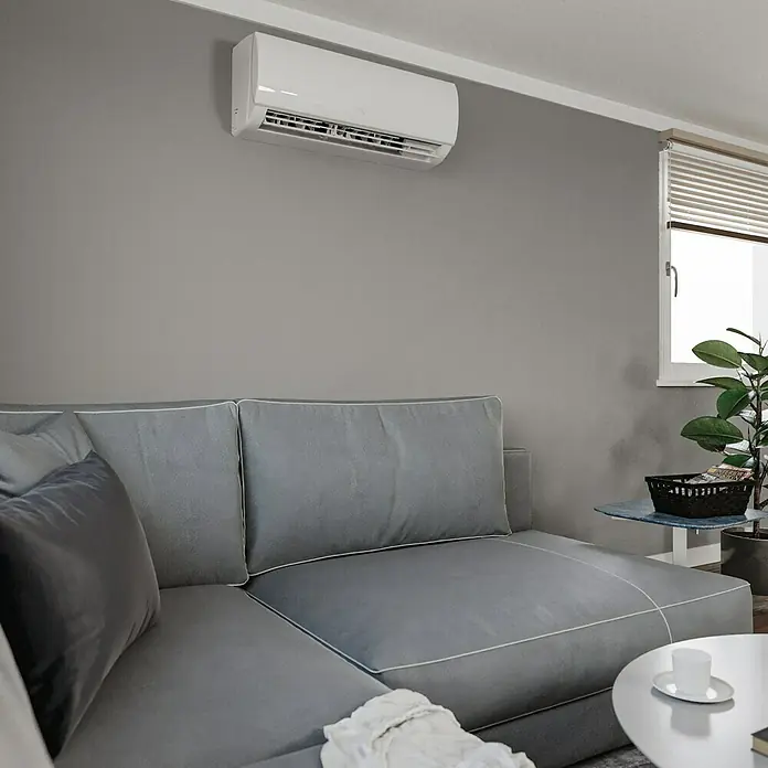 TCL Inverter-Klimasplitgerät TAC-09CHSD/TPG11 - Kühlleistung: 1.380 W - 3.300 W, Heizleistung: 3.360 W, Raumgröße: 26 m², Passend für: Räume bis ca. 26 m² - Moderne Klimaanlage an grauer Wand über grauem Sofa. Sorgt für angenehme Kühle und fügt sich nahtlos in den Wohnraum ein.