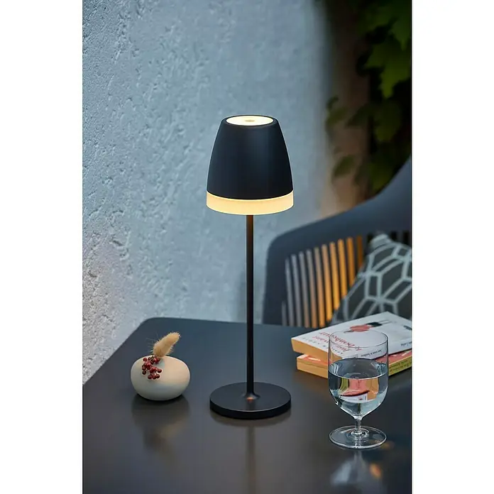 Lavida Akku-Tischleuchte Loria - 2 W, Schwarz, Warmweiß - Tischleuchte aus schwarzem Metall mit warmweißem Licht, neben Dekoration und Glas mit Wasser, für gemütliche Atmosphäre.