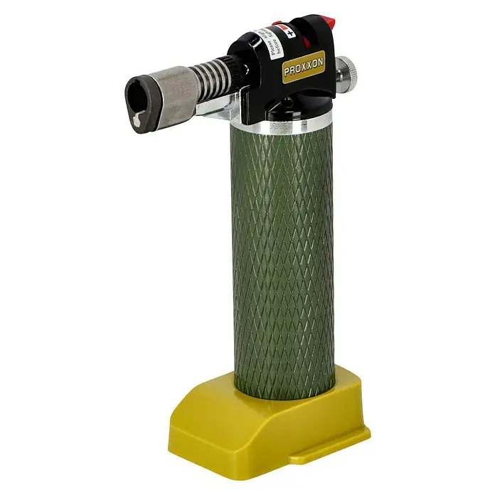 Proxxon Brenner Microflam MFB/E -  - Ein Proxxon Lötbrenner auf gelbem Ständer. Der Brenner hat einen olivgrünen, geriffelten Griff und einen schwarzen Kopf mit silbernen Details.
