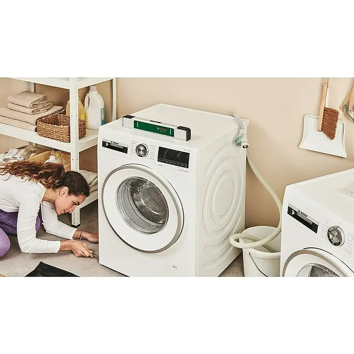 Bosch Easy Wasserwaage EasySpiritLevel - L x B x H: 40 x 3,2 x 6,4 cm, Kunststoff, Grün, Silber - Eine Frau justiert eine weiße Bosch Waschmaschine der Serie 6 mit einer Wasserwaage, um einen korrekten Stand sicherzustellen.