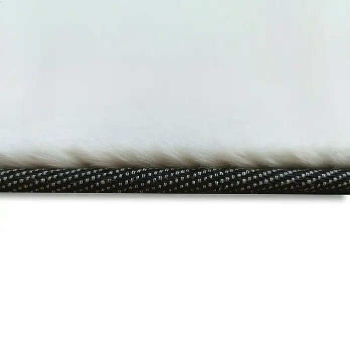 Alfombra de pelo corto Tiana - Crudo, 110 x 60 cm - Primer plano de una elegante alfombra con fibras blancas y suaves y un borde resistente con un patrón oscuro, perfecta para un espacio habitable acogedor.