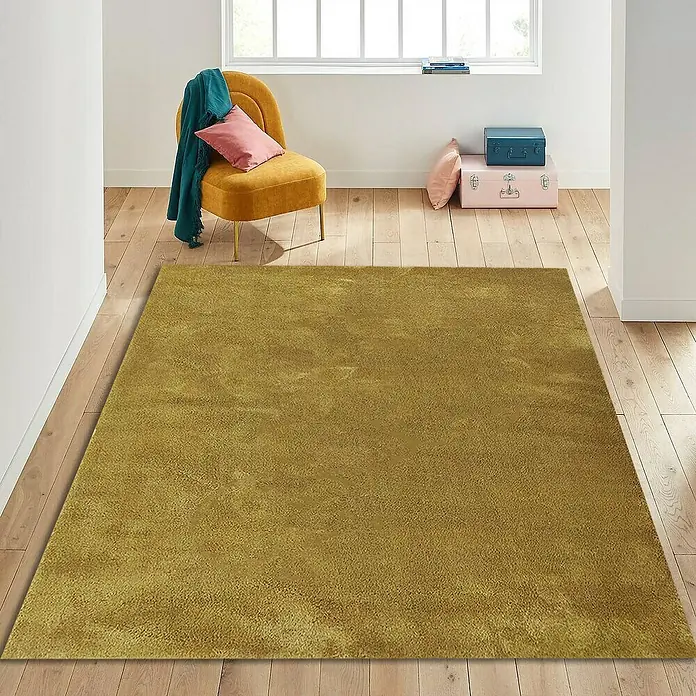 Alfombra de pelo corto Toscana - Mostaza, 230 x 160 cm, 100% Poliéster - Primer plano de una alfombra dorada en una habitación con suelo de madera, que irradia calidez y confort.