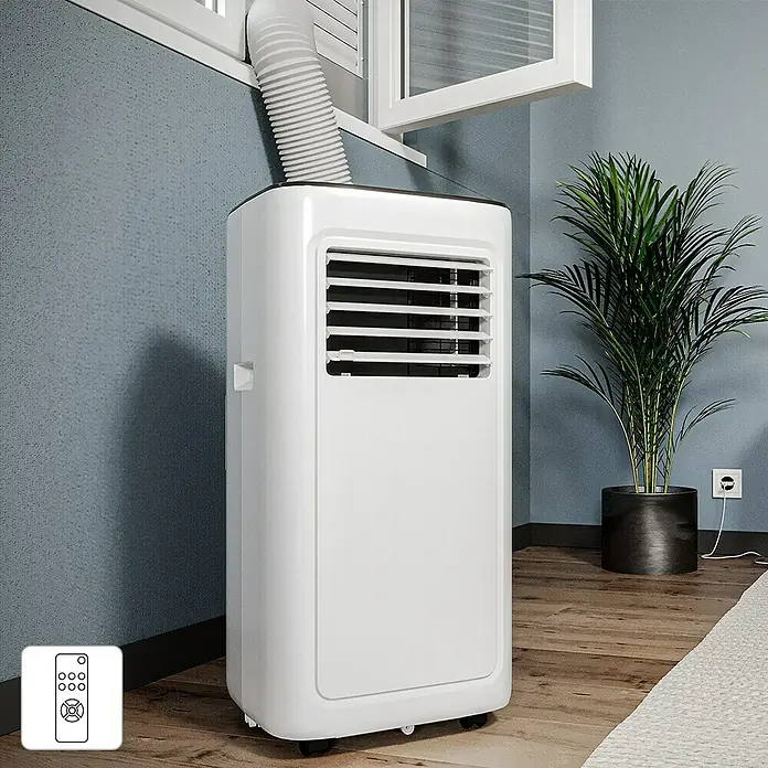 Voltomat Aire acondicionado portátil Boreas - 2.000 W, Tamaño de la estancia: 20 m², Blanco/Negro - Un aire acondicionado portátil blanco con una manguera de escape que se extiende desde una ventana se encuentra en una habitación decorada modernamente.